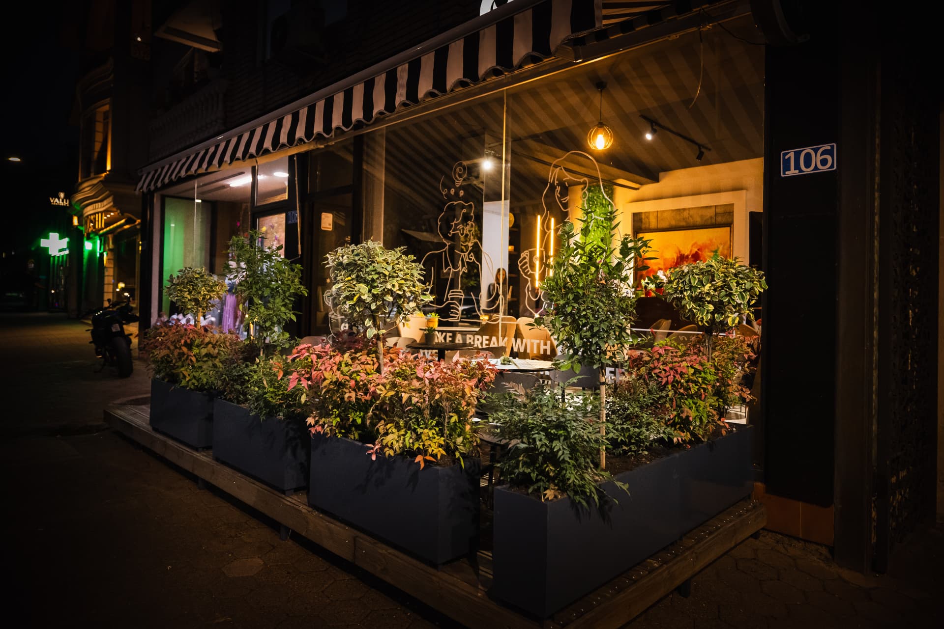 ENO-AD Coffee glass front glowing after dark with planters outside