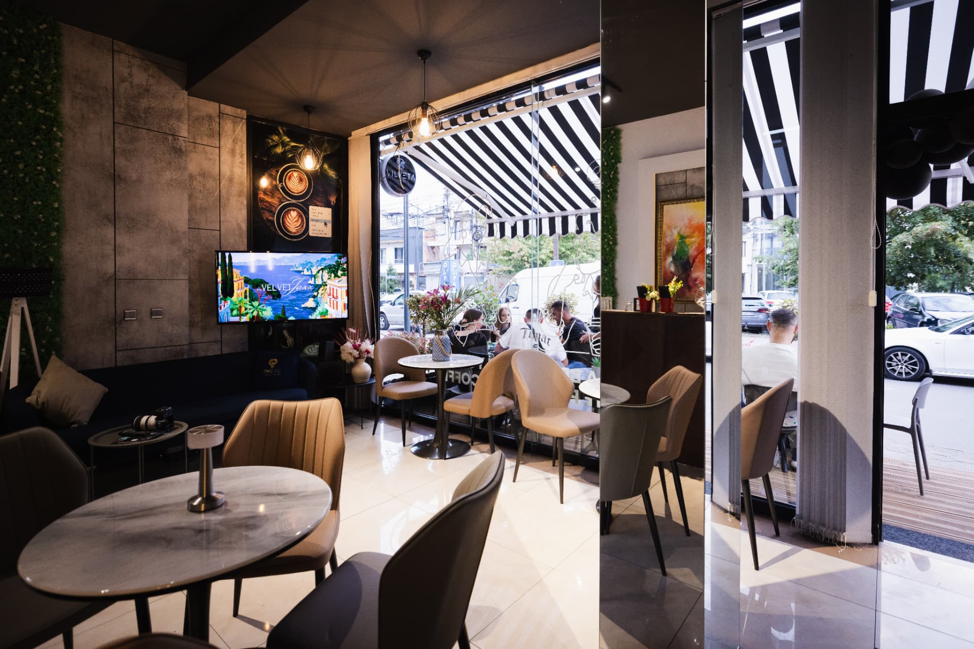Bright interior of ENO-AD Coffee in Pejë with a large window and warm upholstered seating