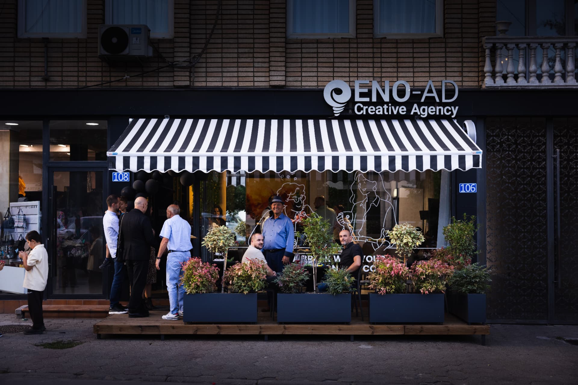 Guests seated under the striped awning outside ENO-AD Coffee