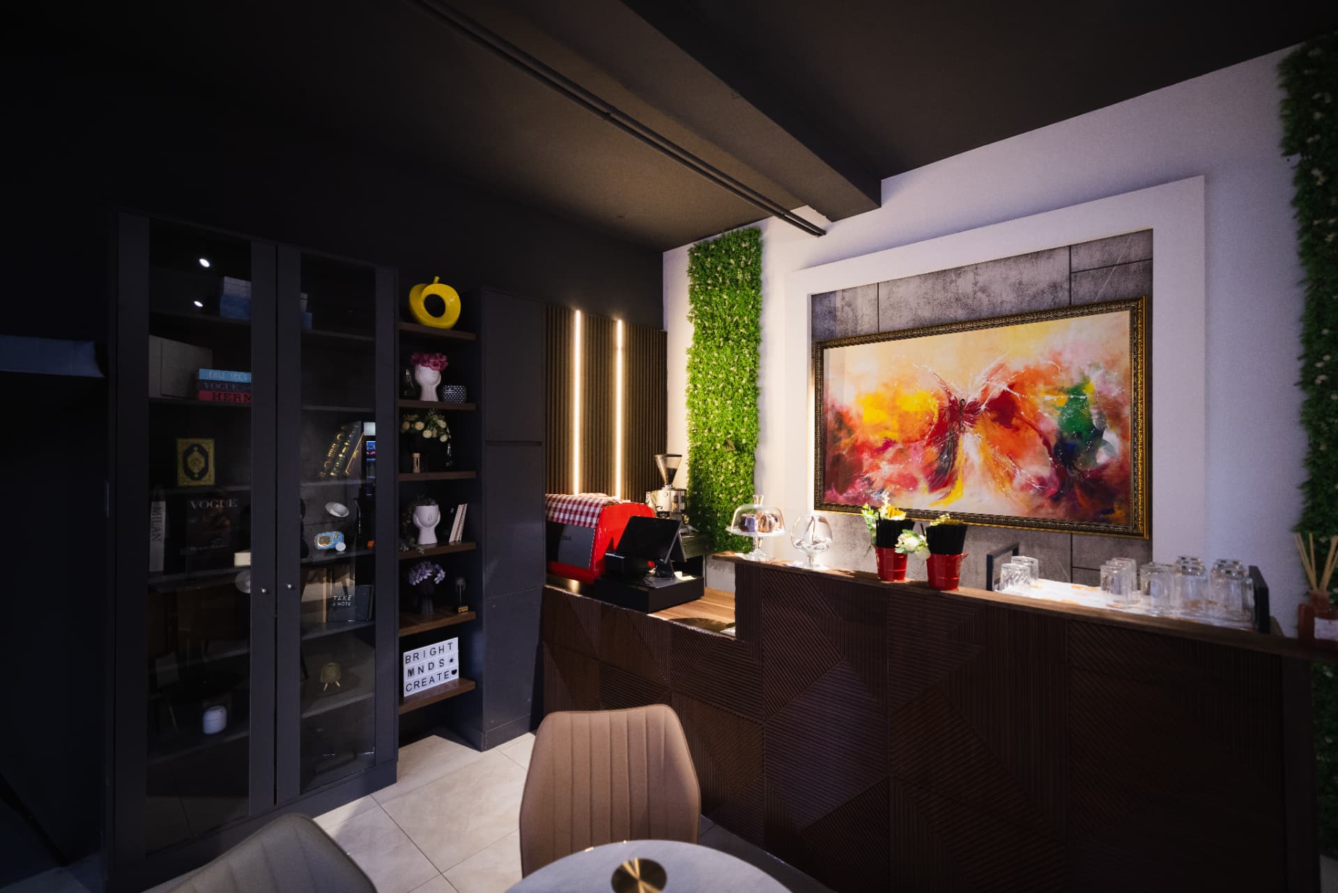 ENO-AD Coffee counter with back shelving, greenery and a colourful painting