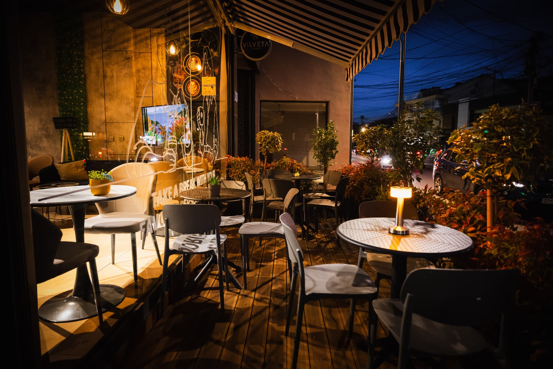Outdoor table at ENO-AD Coffee lit by a small glowing lamp in the evening