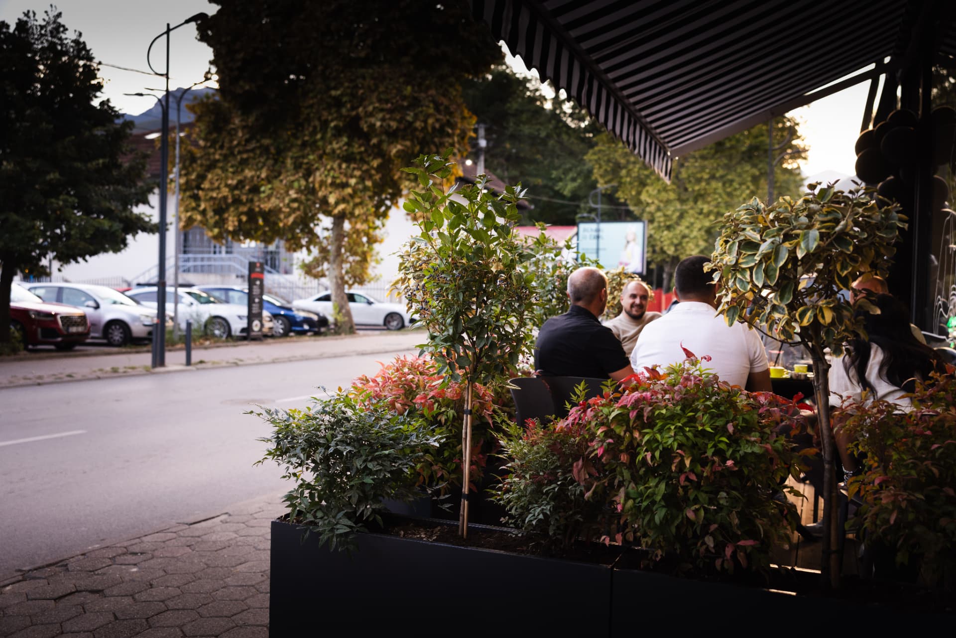 People seated on the ENO-AD Coffee terrace seen through foliage